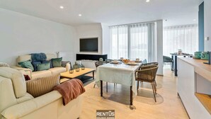 A modern living room with a sofa, dining table, and kitchen area. - Sol i Mar - located in the heart of Westende (Middelkerke)