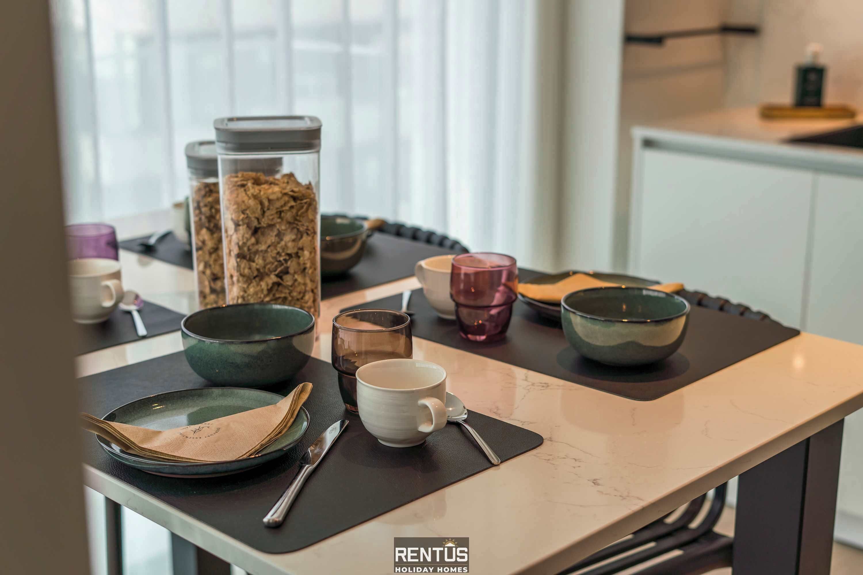 A dining table with various dishes and utensils, a glass jar with snacks, and a bowl.