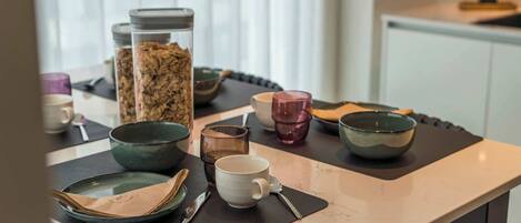 A dining table with various dishes and utensils, a glass jar with snacks, and a bowl.