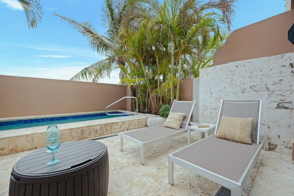 Un espace piscine aménagé sur le toit, avec des chaises longues, une petite table et un verre, et une vue dégagée sur le ciel.