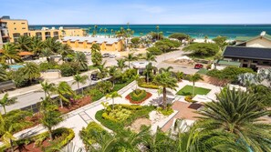 A resort with a pool, palm trees, and a view of the ocean.