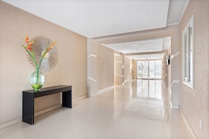 A spacious, well-lit hallway with a bench and a decorative vase. - Luxe Beach Condo Le Vent Townhouse 17 by Bocobay (Noord)