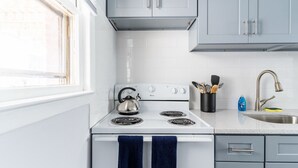 A kitchen with white cabinets, a stove, and a sink. - The Kelly Studio · Near Mystic, Casinos + USCGA (Groton)