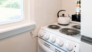 Une cuisine avec des meubles blancs, une cuisinière et une fenêtre.