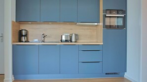 A modern kitchen with blue cabinets, a wooden countertop, a coffee maker, a kettle, and an oven. - Villa Baltic Star Ferienwohnung 10 (Börgerende-Rethwisch)