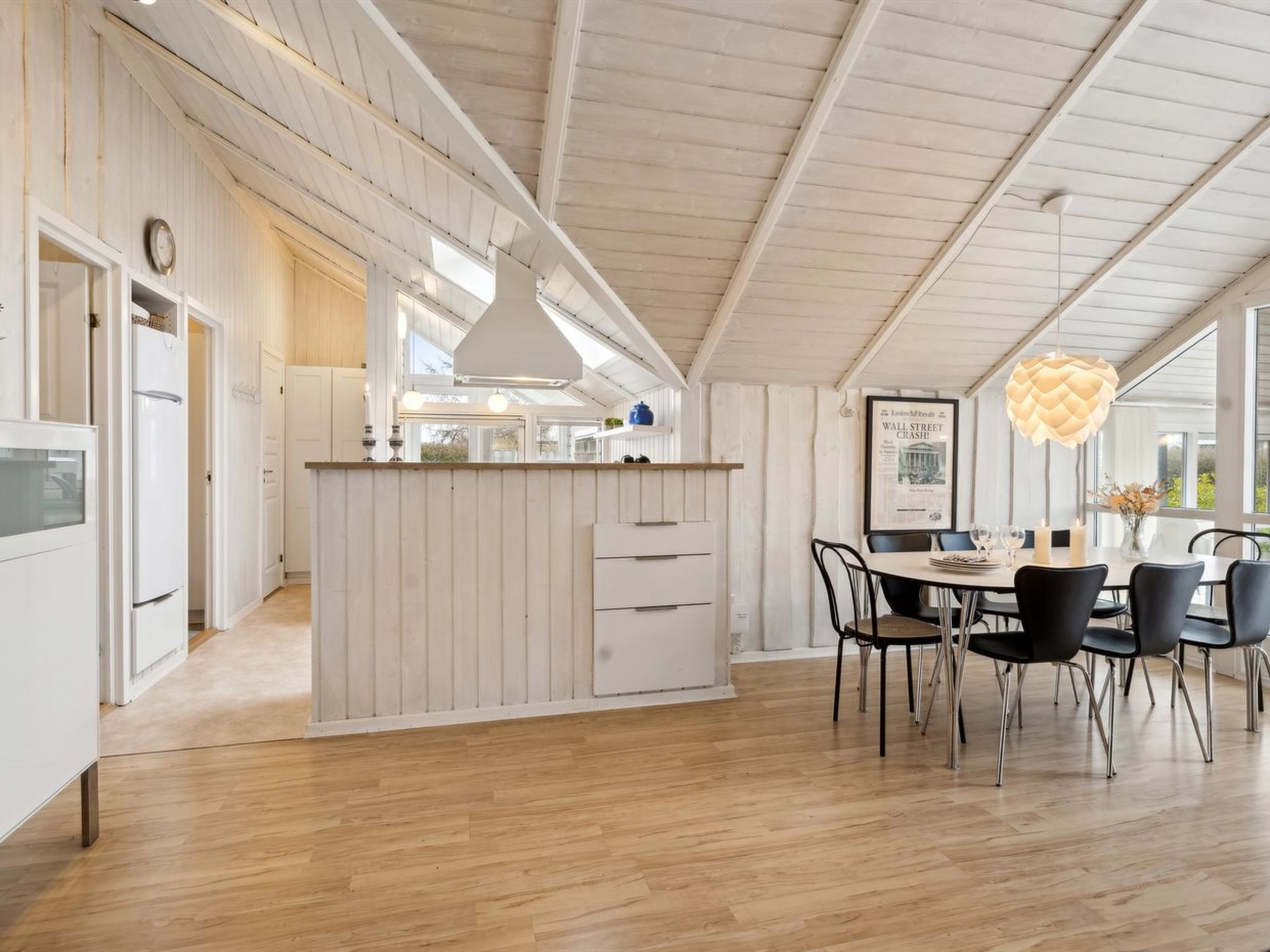 Een moderne keuken met witte kasten, een centraal eiland en een eetgedeelte met een ronde tafel en stoelen.