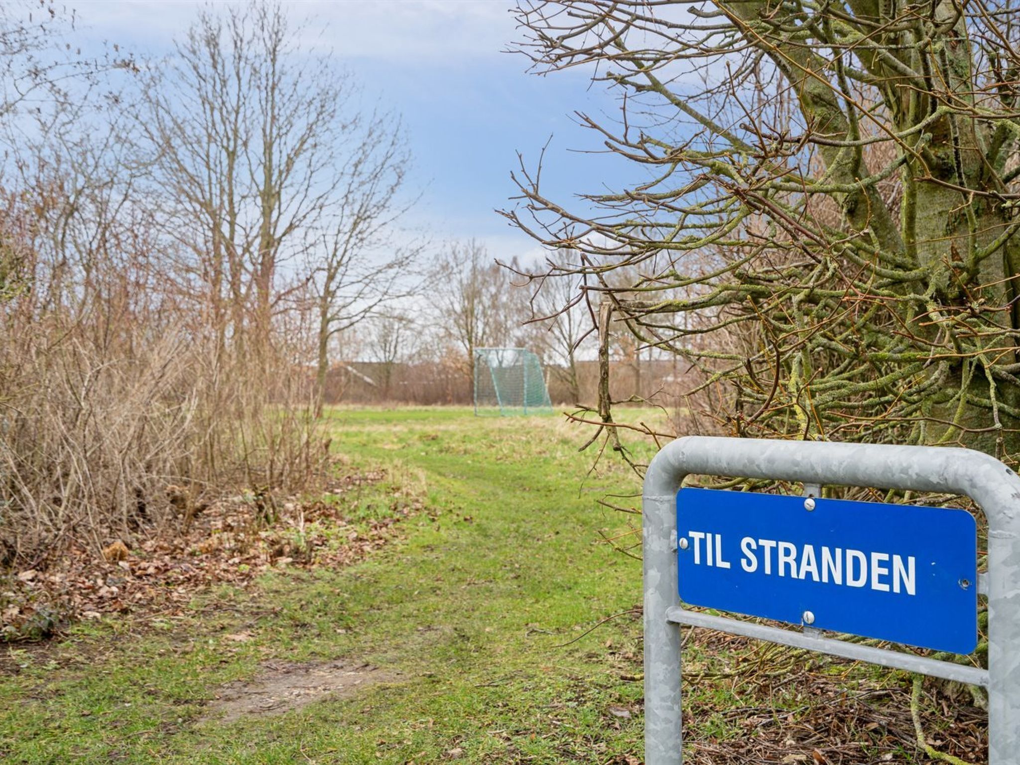 Un panneau indiquant la direction ou l’emplacement de la plage, avec l’inscription « TIL STRANDEN ».