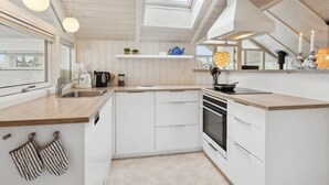 A modern kitchen with white cabinetry, a built-in oven, a sink, and a skylight. - "Chrisse" - 250m from the sea by Interhome (Otterup)