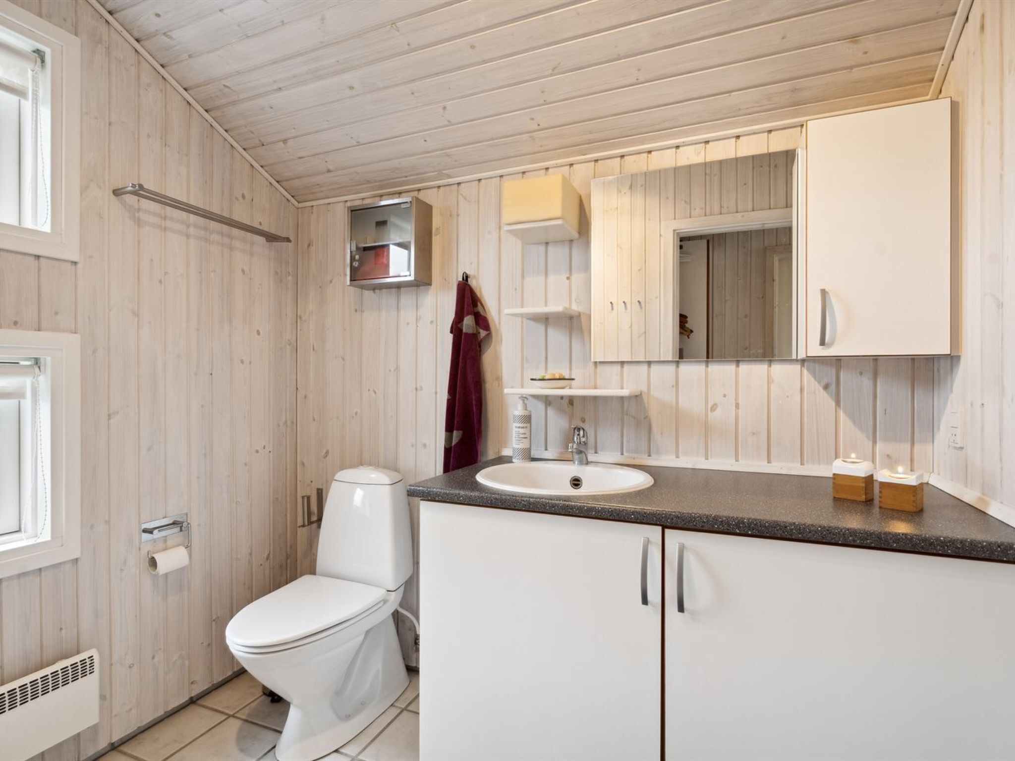 A modern bathroom with a toilet, sink, and wooden panel walls.