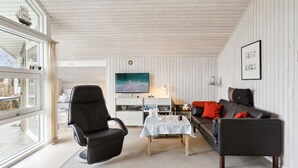 A modern living room with a black leather sofa, a black leather armchair, a wooden coffee table, and a flat-screen TV mounted on the wall. - "Hereth" - 100m from the sea by Interhome (Otterup)
