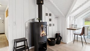 Een modern interieur met een zwart houtvuur, een houten bank, een kleine tafel en een stoel.