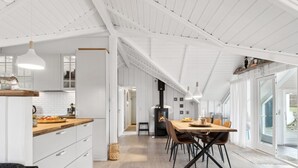 Een moderne keuken met witte kasten, een houten aanrecht en een eethoek met een grote tafel en stoelen.