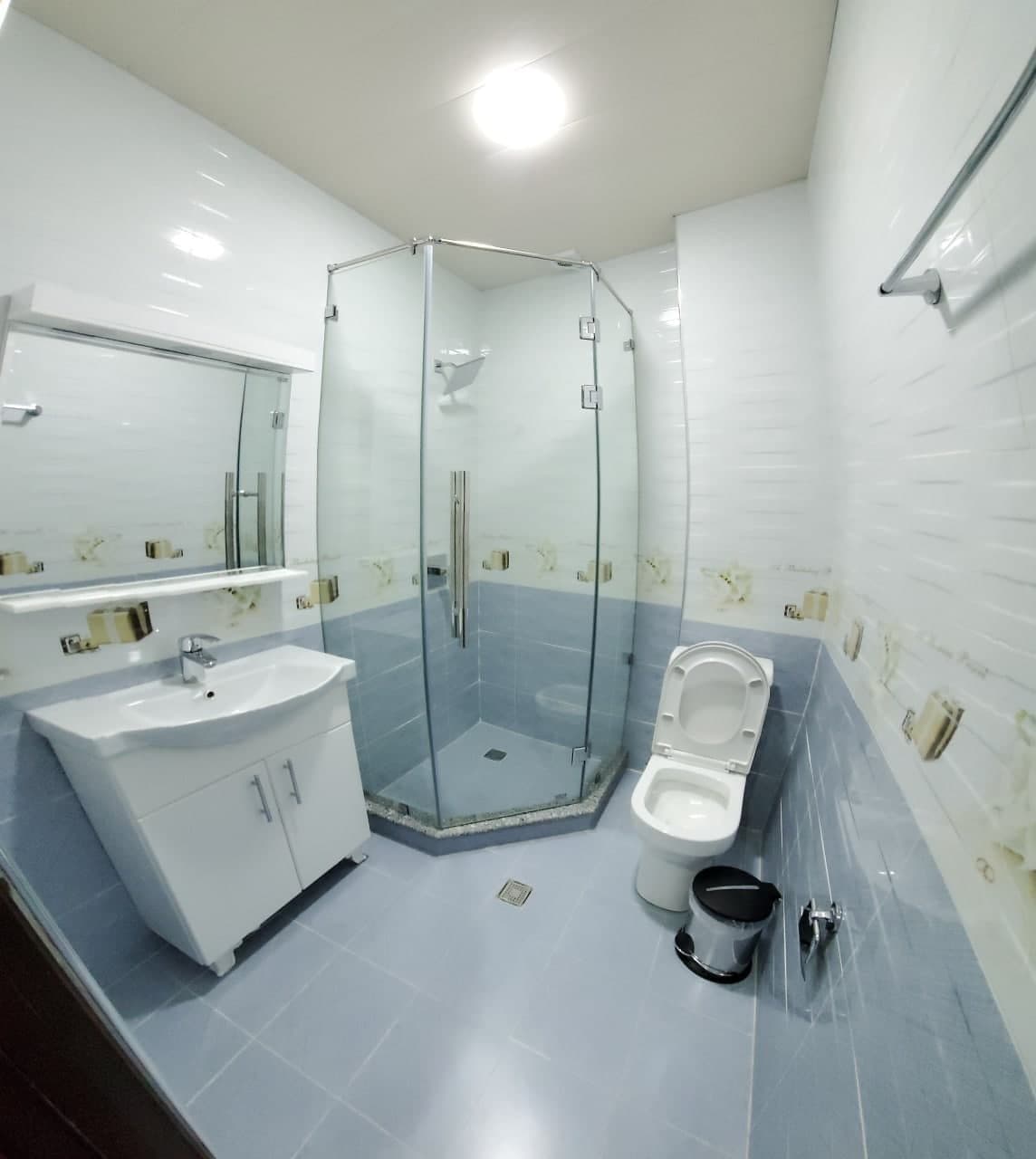 Une salle de bain moderne avec une douche à parois de verre, un lavabo avec un miroir et des toilettes.