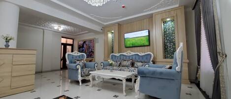 A spacious living room with a chandelier, a television, and a large window with a view of a field.