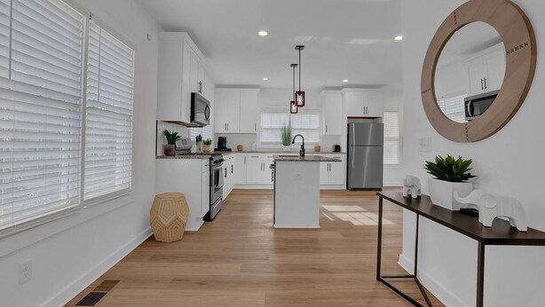 A modern kitchen with white cabinets, a central island, and a round mirror on the wall. - Atlanta Hamilton House, 7 Beds (Atlanta)