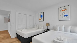 A hotel room with two beds, white bedding, a nightstand with a lamp, and abstract art on the walls. - Atlanta Hamilton House, 7 Beds (Atlanta)