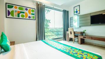 Une chambre d’hôtel avec un lit, un bureau, une chaise, une télévision et une fenêtre avec des rideaux.