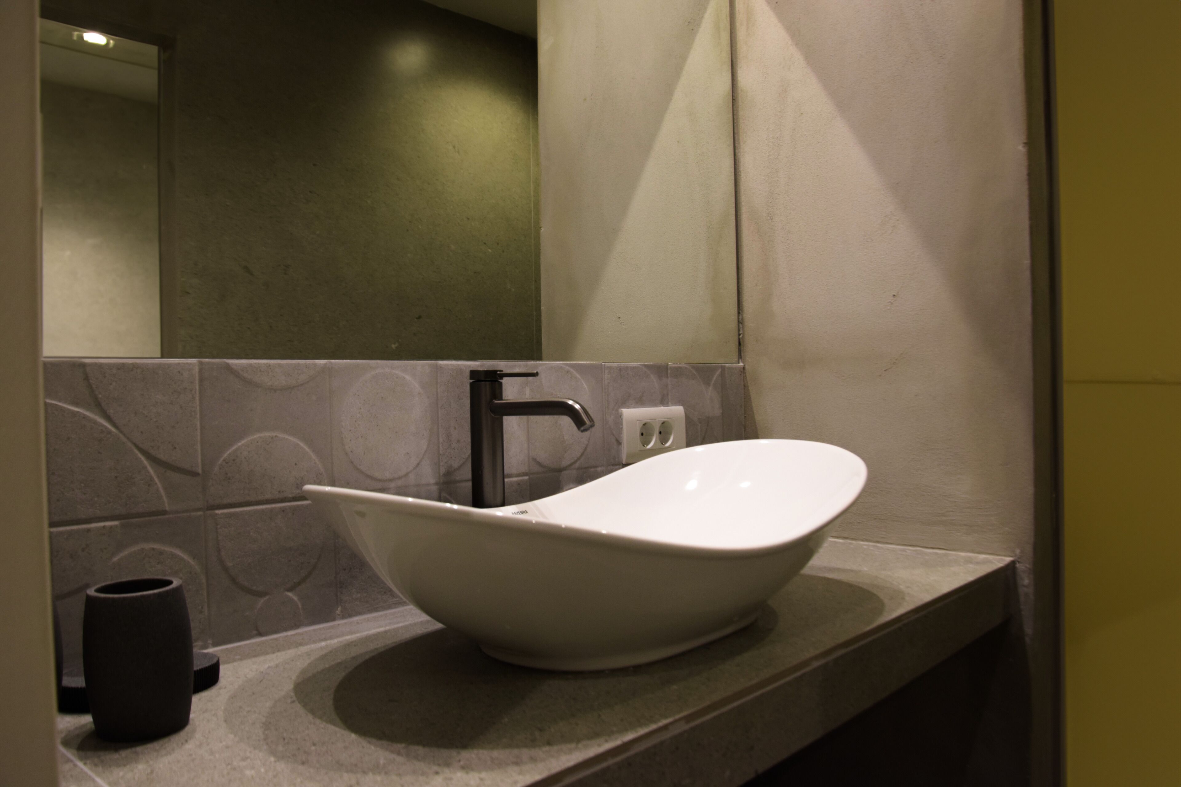 Un baño moderno con un lavamanos grande y blanco, un solo grifo y un espejo encima.