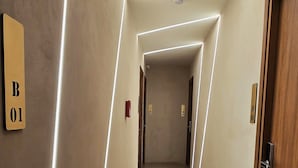 A corridor with a modern design, featuring a sign with the number "B01" on the left wall, a wooden door on the right, and a tiled floor. - 99 Adrianou Luxury Urban Stay (Athens)