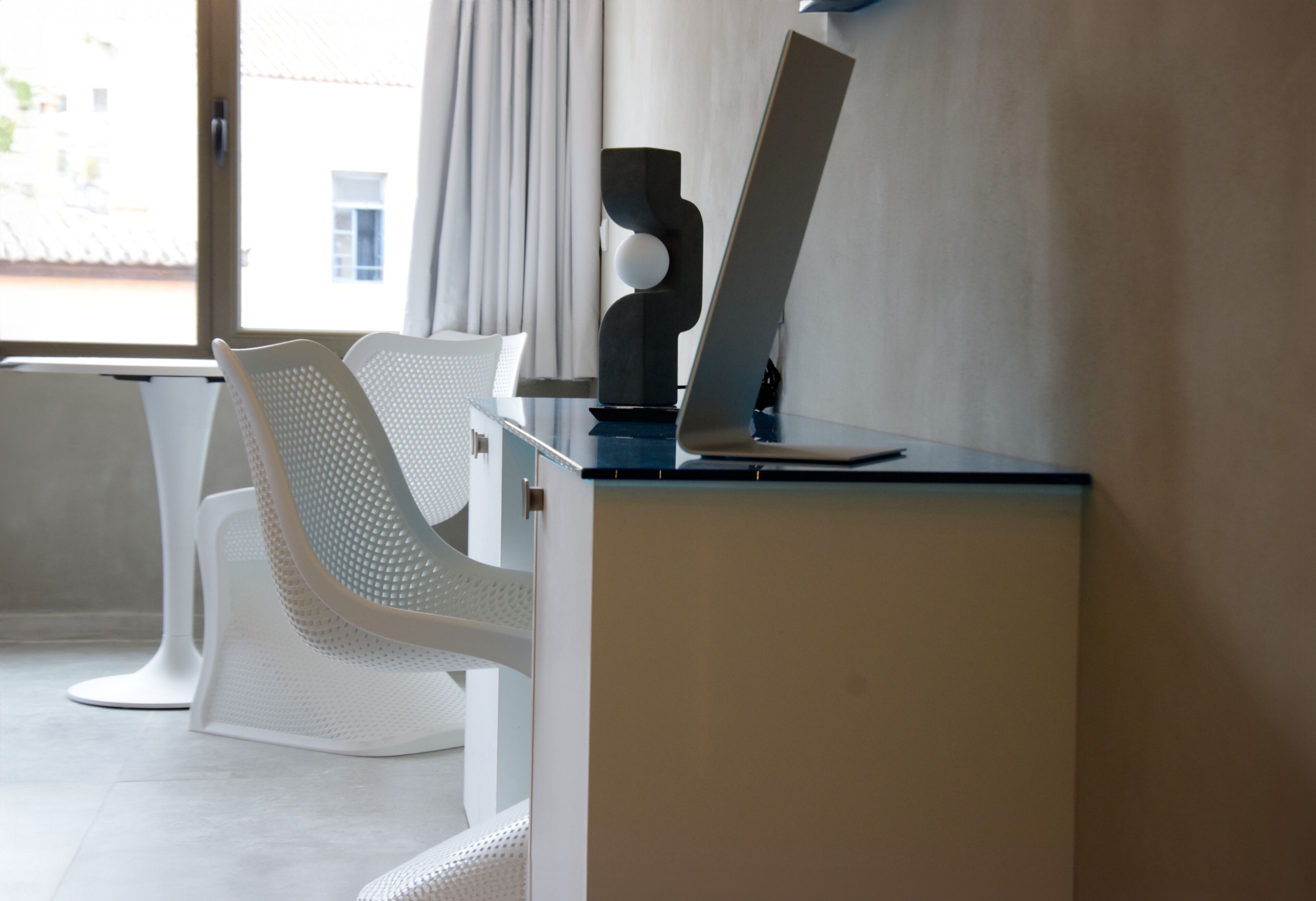 A modern hotel room with a desk, a laptop, and a white chair.