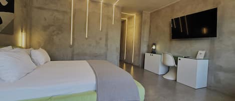 A modern hotel room with a large bed, bedside tables, a flat-screen TV, and a small refrigerator.