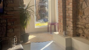 A room with a brick wall, a large window, a potted plant, and a small table. - Appartement Entier, Comme un Loft, Chez Ariane on sy Sent Bien ! (Mittersheim)