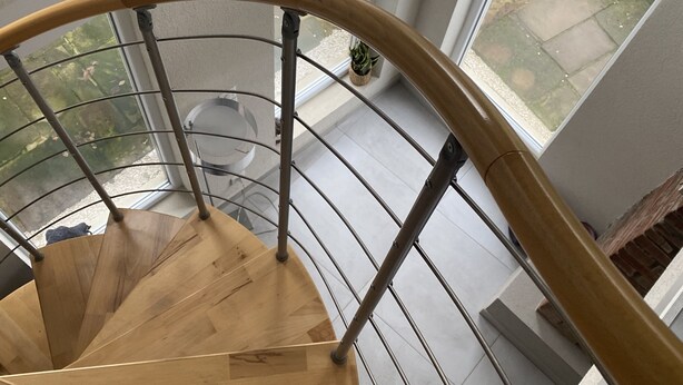 A spiral staircase with wooden steps and metal railings, leading to a balcony with large windows and a view of the outdoors. - Appartement Entier, Comme un Loft, Chez Ariane on sy Sent Bien ! (Mittersheim)