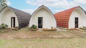 Tre edifici bianchi, con tetti ad arco grigi e rossi, disposti in fila con piccoli giardini davanti.
