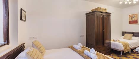 A hotel room with two beds, a wardrobe, and a window.