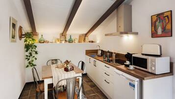 A compact kitchen with a dining area, featuring a microwave, coffee maker, and various kitchen utensils.
