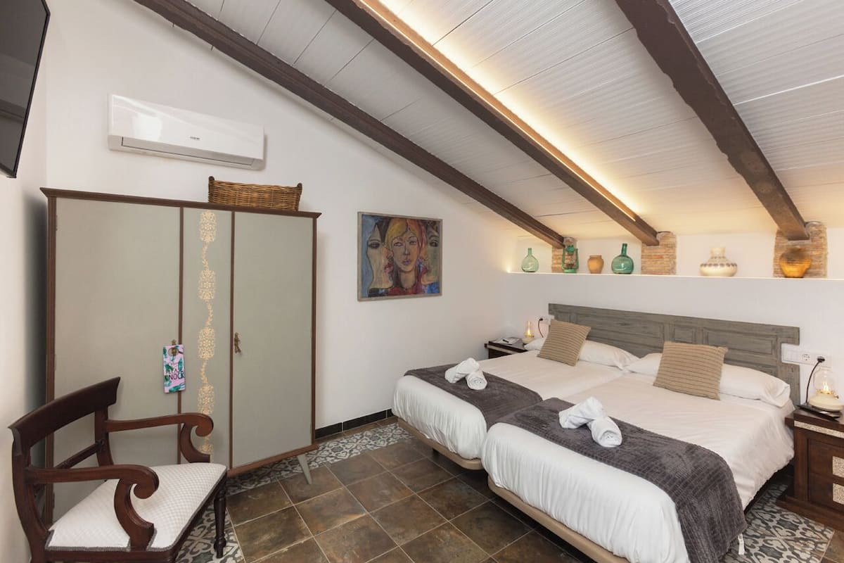 Een slaapkamer met een bed, een kledingkast, een stoel en een schilderij aan de muur.