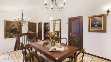A dining room with a wooden table, chairs, a chandelier, and framed artwork on the walls.