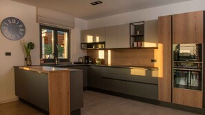 Une cuisine moderne dotée d’un îlot central, d’appareils électroménagers intégrés et de nombreux rangements.