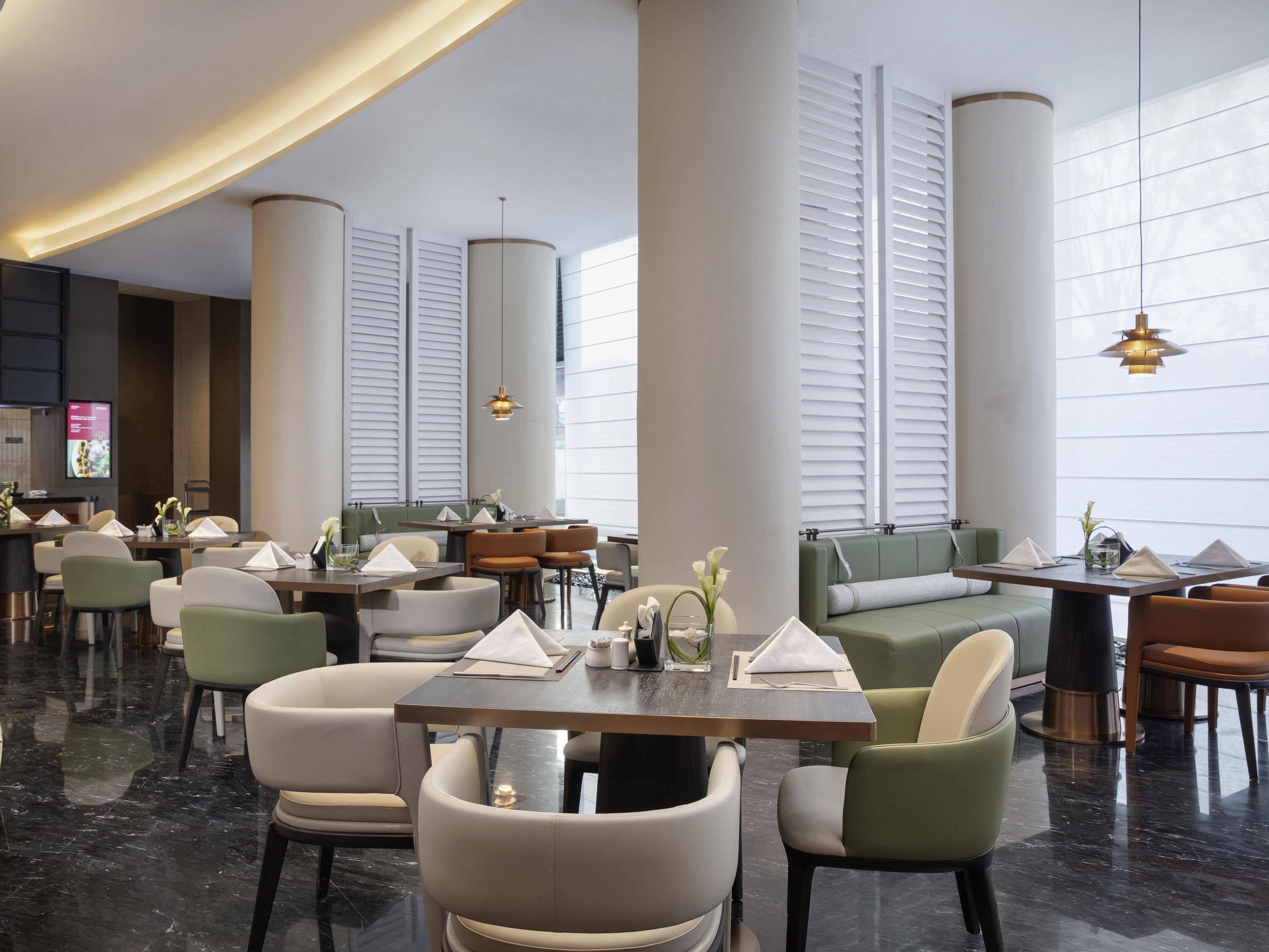 A modern restaurant with high ceilings, large windows, and a variety of seating options including tables and booths.
