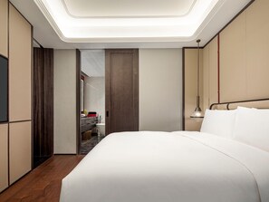 Une chambre d’hôtel avec un grand lit, une coiffeuse avec un miroir et une table de chevet avec une lampe.