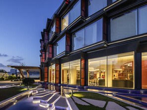 Un hotel moderno con zona de piscina, amplias ventanas y fachada bien iluminada.