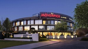 A modern building with a curved facade, large windows, and a prominent sign reading "MÖVENPICK by ACCOR". - Movenpick Qingdao Sunmei (Qingdao)