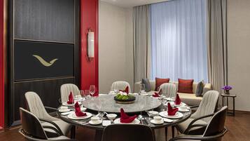 A dining area with a round table set for six, surrounded by chairs.