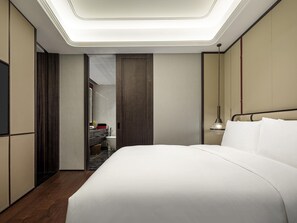 Una habitación de hotel moderna con una cama grande, una tocador con espejo y una lámpara en el techo.