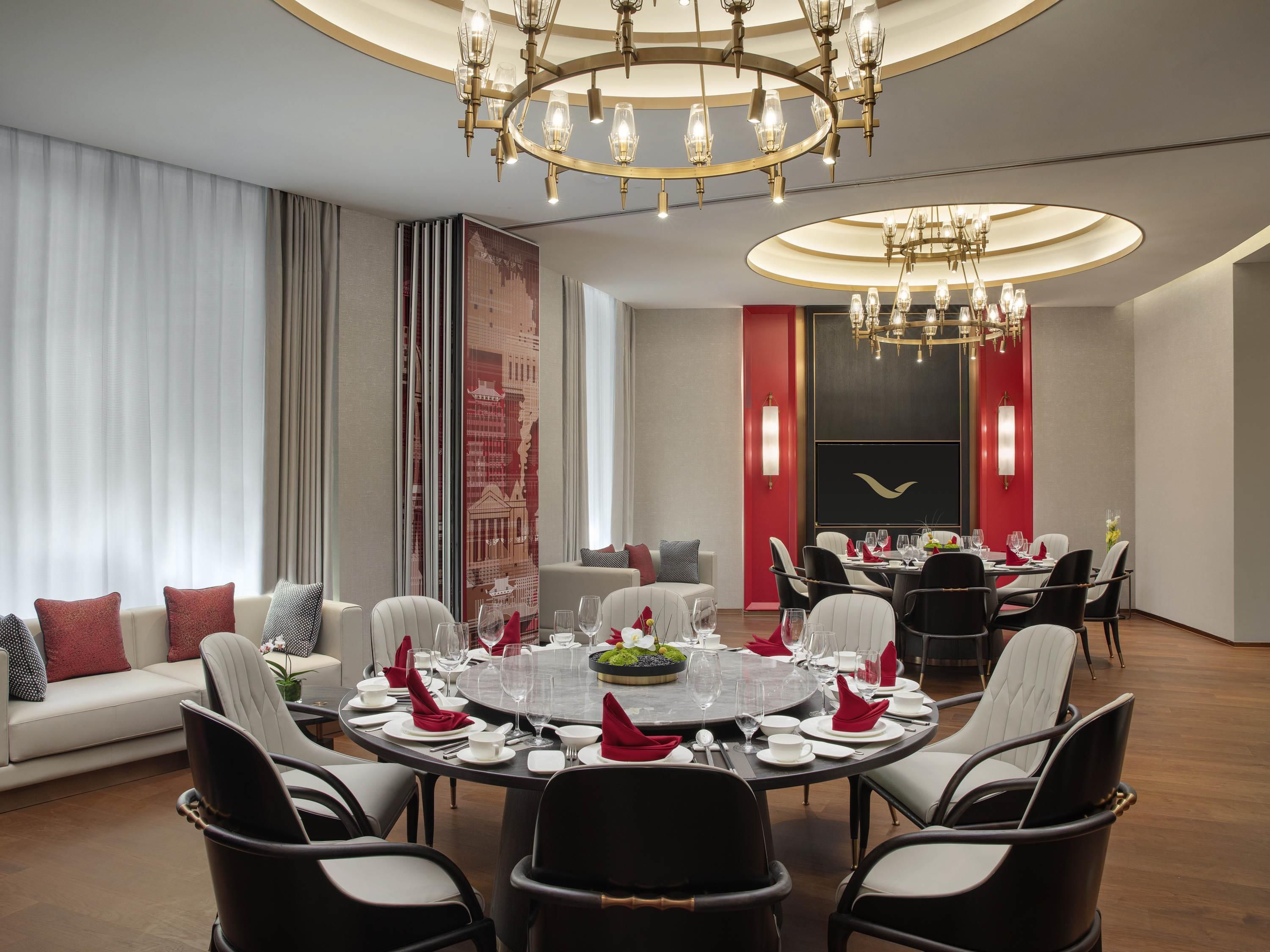 A modern dining room with a round table set for six, surrounded by black and white chairs.