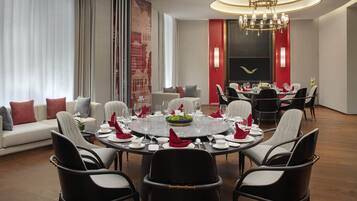 A modern dining room with a round table set for six, surrounded by black and white chairs.