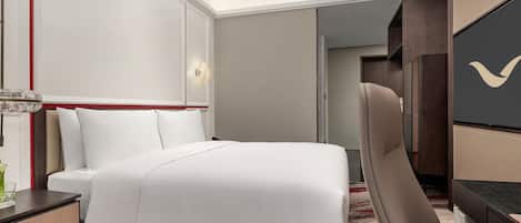Habitación de hotel con una cama bien hecha, un escritorio con silla, un televisor y una puerta que da a otra habitación.