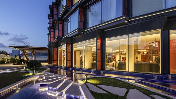 A modern hotel with a pool area, large windows, and a well-lit facade. - Movenpick Qingdao Sunmei (Qingdao)