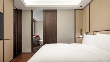 A modern hotel room with a large bed, a vanity with a mirror, and a ceiling light.