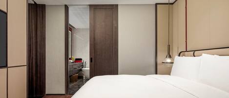 Une chambre d’hôtel moderne avec un grand lit, une coiffeuse avec un miroir et un luminaire au plafond.