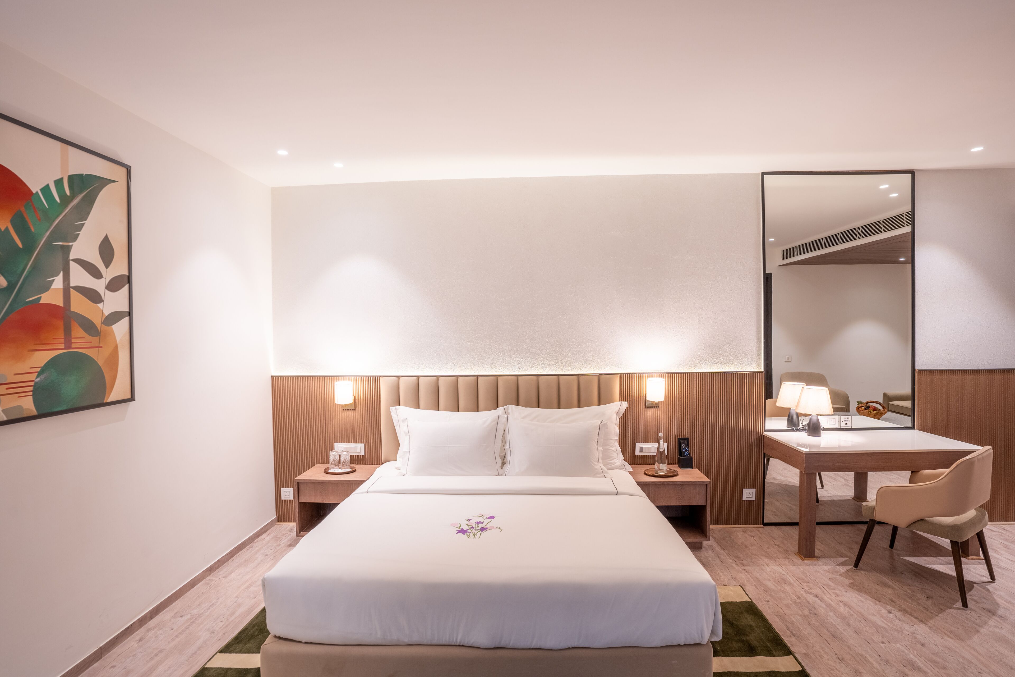 A hotel room with a large bed, bedside tables, a desk, and a chair.
