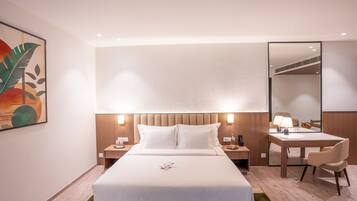 A hotel room with a large bed, bedside tables, a desk, and a chair.