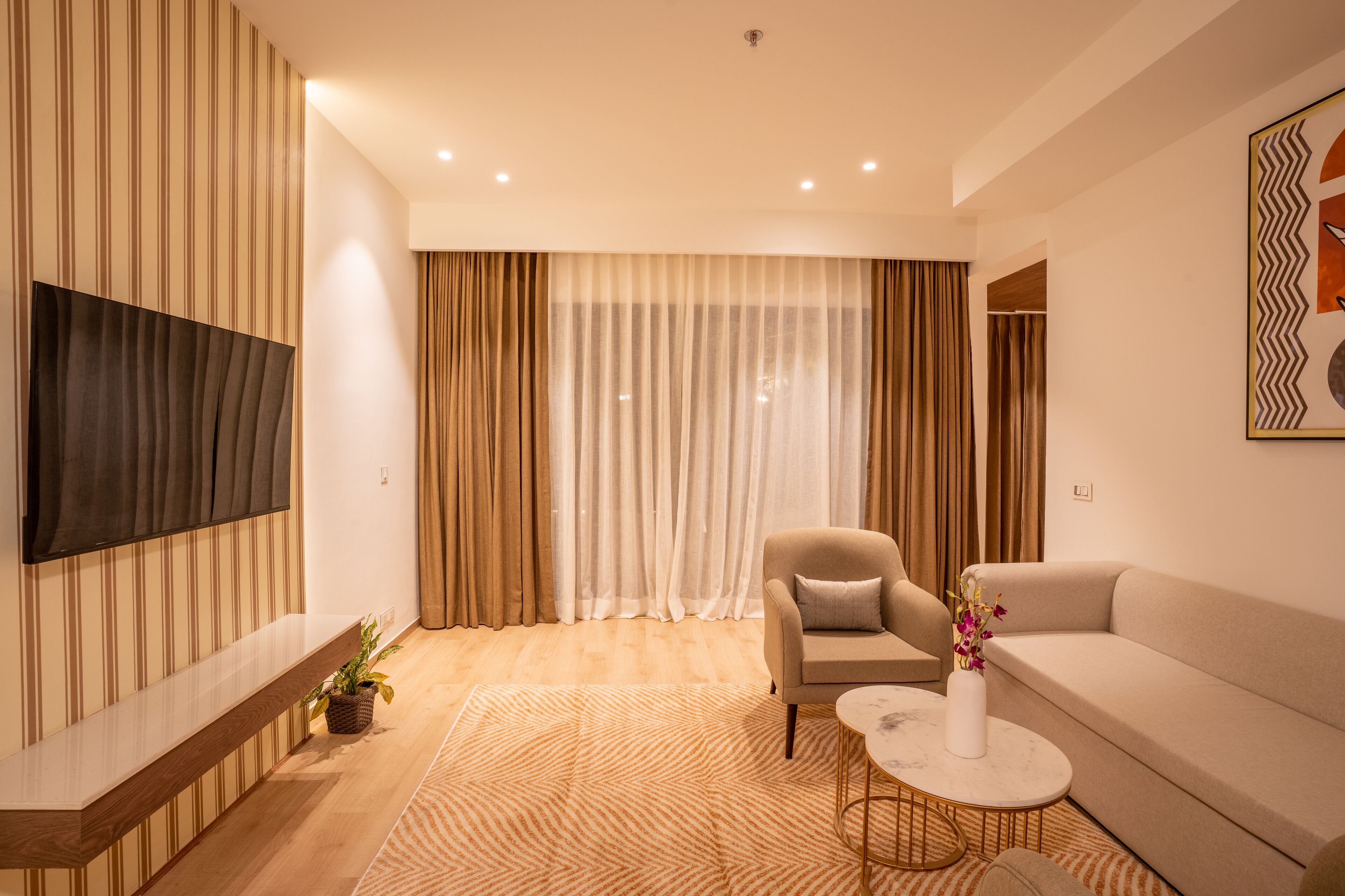 A modern living room with a sofa, armchair, TV, and a decorative vase on a coffee table.