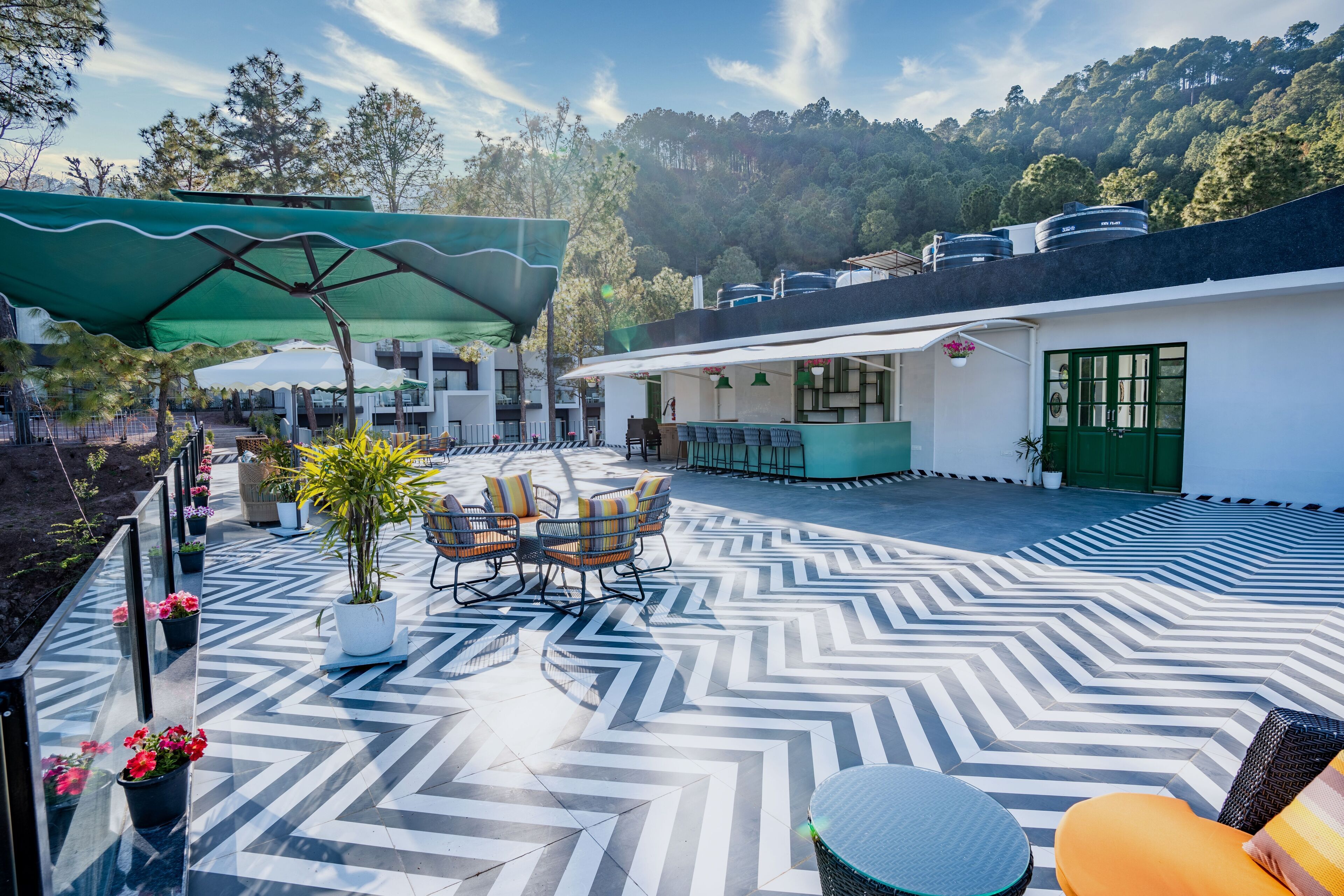 Eine Terrasse mit einem Zickzack-Bodenmuster, Sitzgelegenheiten im Freien und ein Gebäude mit einer grünen Tür.