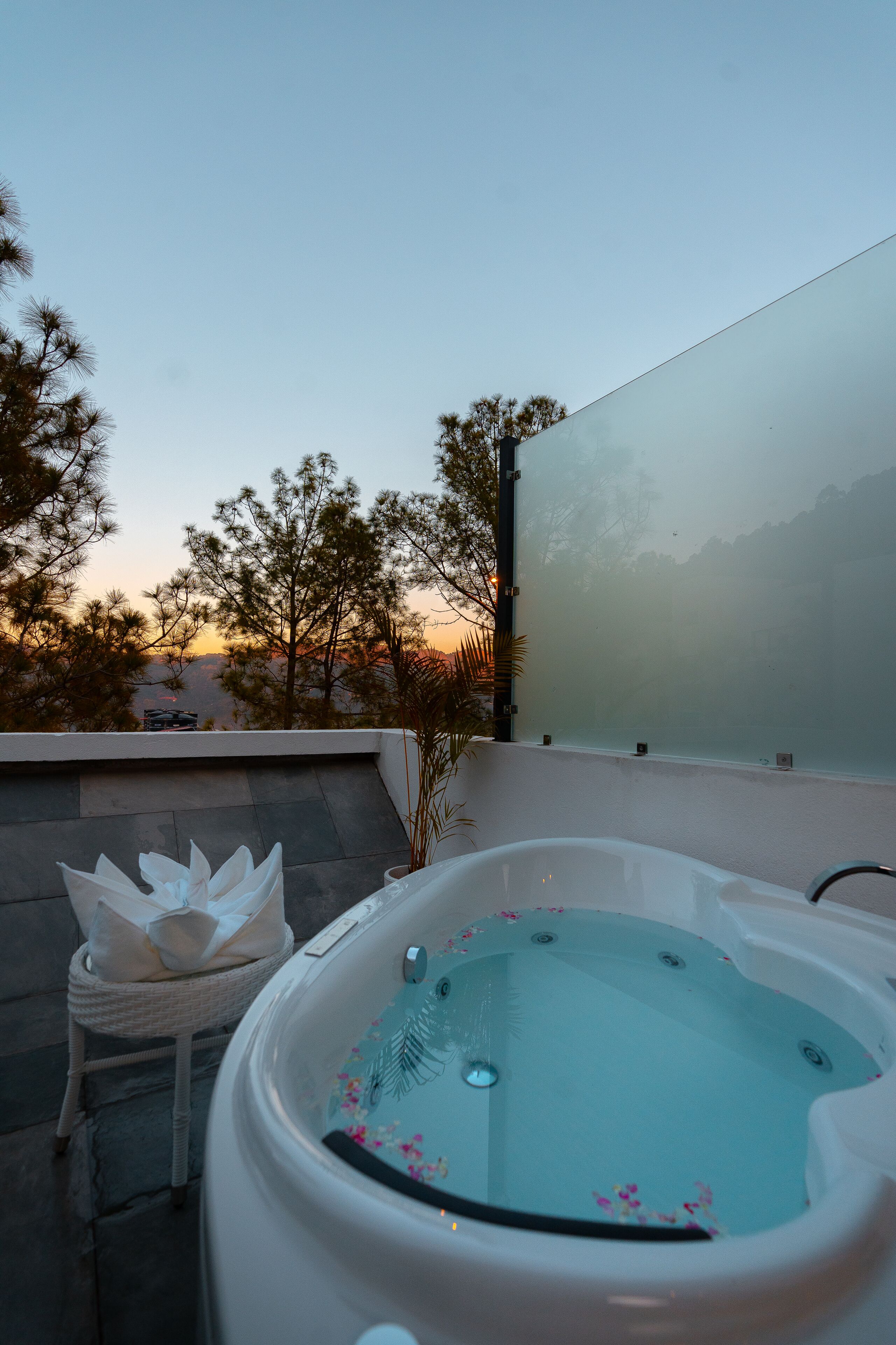A hot tub on a rooftop terrace with a view of trees and mountains in the background.
